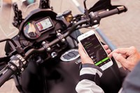 Motorcycle rider using RIDEOLOGY THE APP MOTORCYCLE on their mobile device while sitting on a Kawasaki Motorcycle.