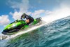 Profile angle of person riding a personal watercraft through a turn on water.