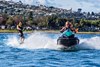 Front angle of person riding a personal watercraft on water while towing wakeboarder.