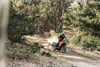Three-quarter angle of person riding a motorcycle down a trail.