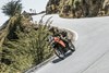 Three-quarter front angle of person riding a motorcycle around a corner.