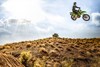 Side angle of a person jumping a motorcycle off-road.