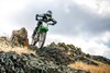 Front angle of a person riding a motorcycle off-road over rocks.