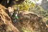 Front three-quarter angle of a person riding a motorcycle off-road.