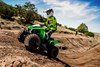 Front three-quarter angle of a person riding an ATV on a track.