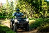 Front three-quarter angle of a person riding an ATV off-road.