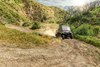 Front three-quarter angle of a person driving a side x side around a corner off-road.