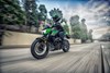 Three-quarter front angle of a person riding a motorcycle on a city street.