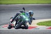 Three-quarter front angle of a person riding a motorcycle on a racetrack.
