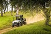 Front three-quarter angle of a person driving a side x side on a dirt trail.