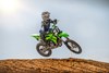 Three-quarter front angle of person riding a motorcycle getting air on a dirt track.