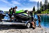 Group of people unloading a Jet Ski into the water.