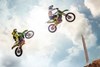 Profile angle of two people getting air on motorcycles.