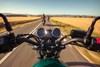 Close up of person riding a motorcycle on a paved road.