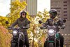 Profile angle of two people riding a motorcycle on a city street.
