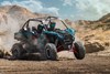 Three-quarter front angle of people riding a side x side on a dirt trail.