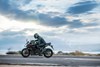 Profile angle of person riding a motorcycle over a paved road.