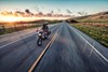 Front angle of people riding a motorcycle on a paved road.