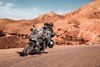 Three-quarter front angle of people riding a motorcycle on a desert highway.