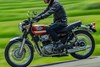 Closeup angle of person riding a motorcycle on a paved road.