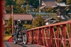 Profile angle of person riding a motorcycle on a bridge.
