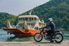 Profile angle of motorcycle staged with person in front of a boat.