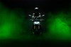 Front angle of a person sitting on a motorcycle in green smoke. 