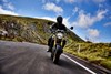 Front angle of a person riding a motorcycle on a highway in the mountains.