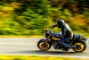 Profile angle of a person riding a motorcycle on a highway in the forest.