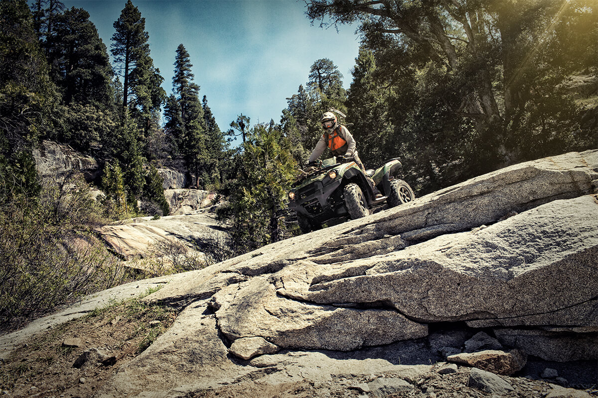 Three-quarter front angle of a person riding an ATV off-road.
