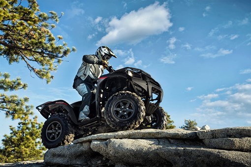 Three-quarter front angle of a person riding an ATV off-road. opens in a new window