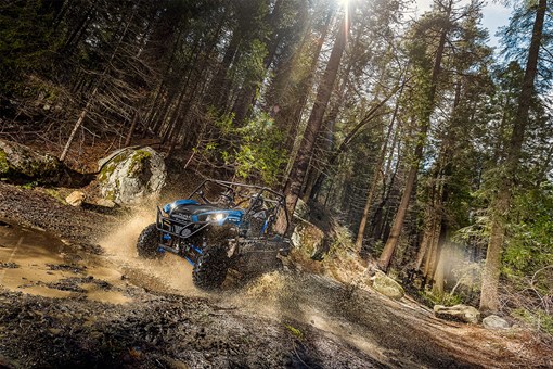 Three-quarter front angle of a person driving a side x side off-road. opens in a new window