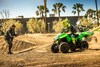 Side front angle of a person riding an ATV on a closed course with parental supervision.
