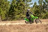 Front three-quarter angle of a person riding a motorcycle on a trail.