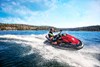 Three-quarter front angle of a person on a personal watercraft on the water by a forest. 