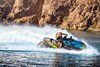 Profile angle of a person on a personal watercraft on the water with mountains in the background.