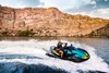 Overhead angle of a person on a personal watercraft on the water with cliffs in the background.