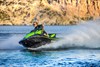 Three-quarter front angle of a person turning on a personal watercraft on the water. 