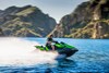 Side angle of a person on a personal watercraft on the water with hills in the background.