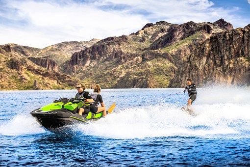 Front three-quarter angle of a person on a personal watercraft on the water with a wake boarder. opens in a new window