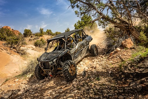 Three-quarter front angle of a person driving a side x side down a rugged trail. opens in a new window