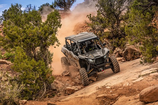 Three-quarter front angle of a person driving a side x side on a curvy off-road trail. opens in a new window