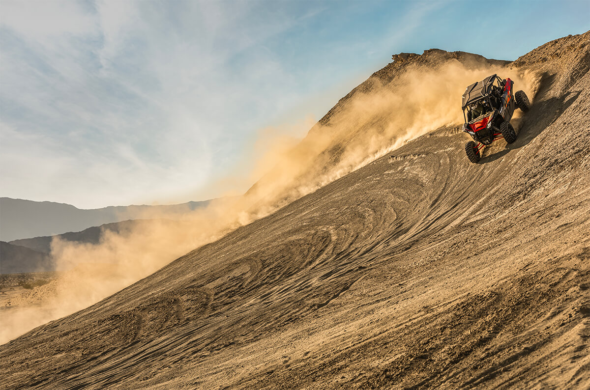 Three-quarter front angle of a person making a wide turn in a side x side off-road.