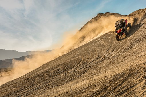 Three-quarter front angle of a person making a wide turn in a side x side off-road. opens in a new window