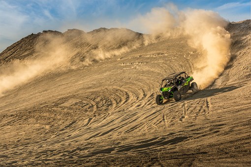 Three-quarter front angle of a person making a wide turn in a side x side on a dirt hill. opens in a new window
