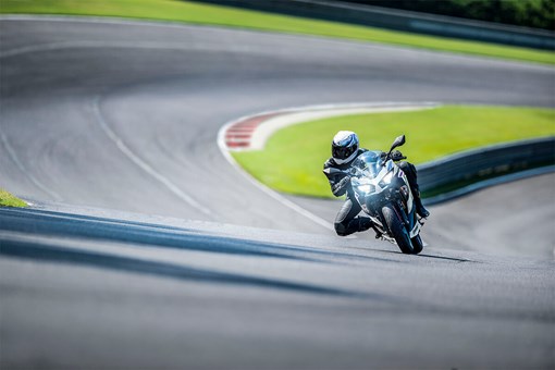 Front angle of a person riding a motorcycle on a racetrack. opens in a new window