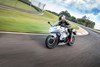 Front three-quarter angle of a person riding a motorcycle on a racetrack.