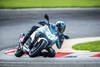 Three-quarter front angle of a person riding a motorcycle on a racetrack.