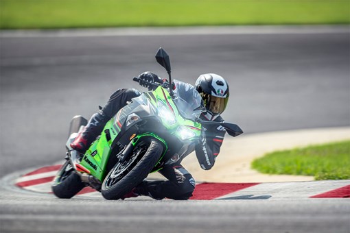 Three-quarter front angle of a person knee dragging around a corner on a motorcycle at a track. opens in a new window