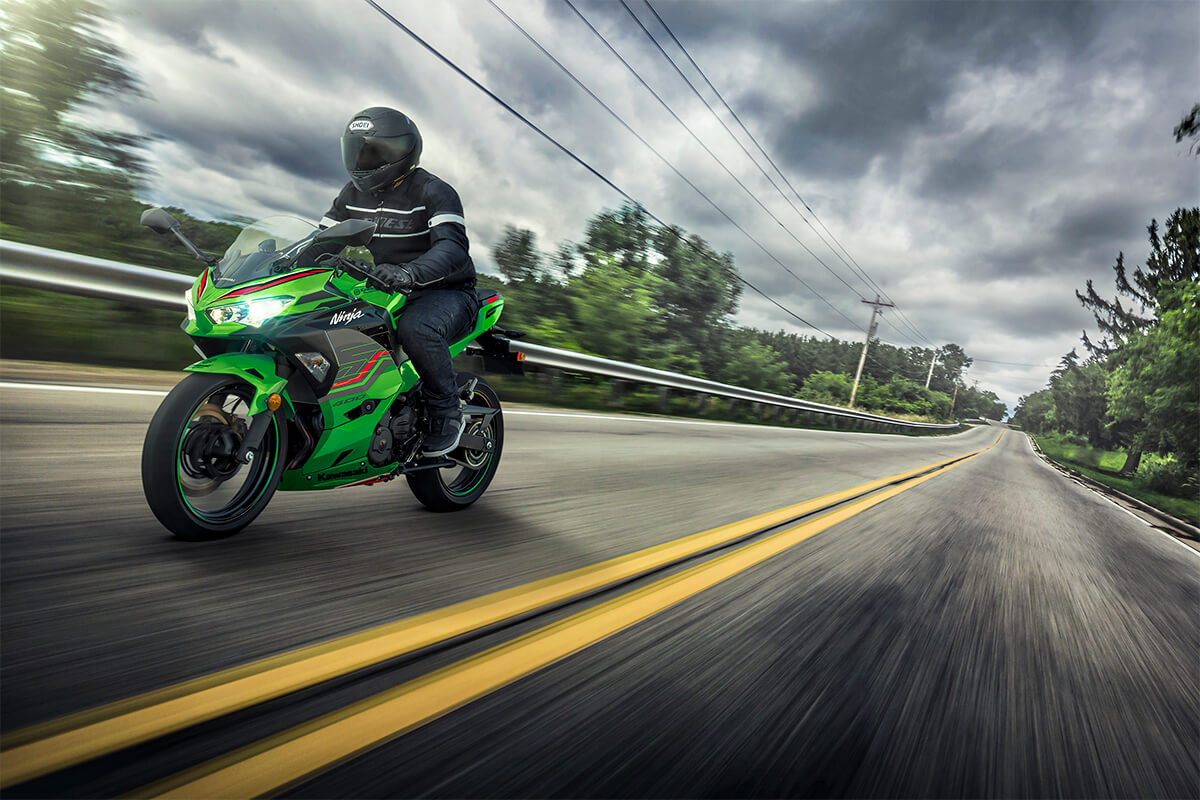 Three-quarter front angle of a person riding a motorcycle down a highway on a cloudy day.